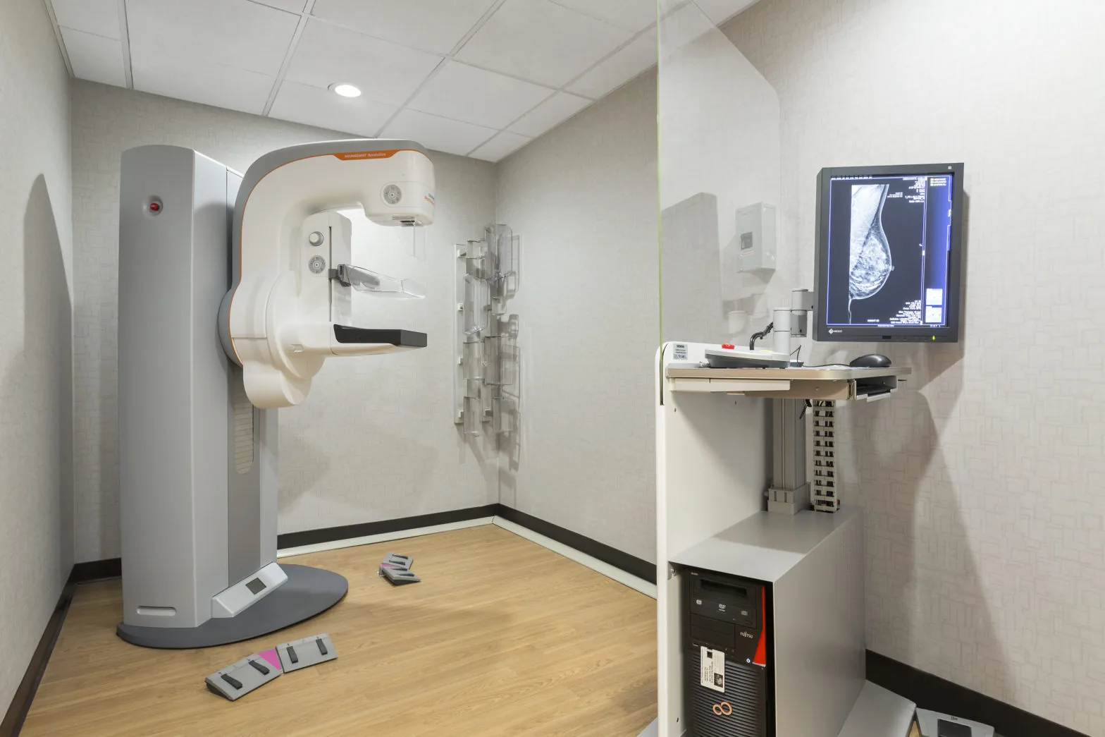 Mammography unit in an exam room with a review monitor beside it