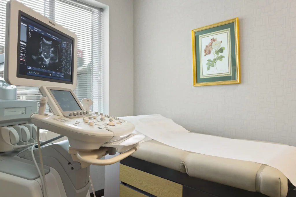 Ultrasound system beside an exam table in an ultrasound room